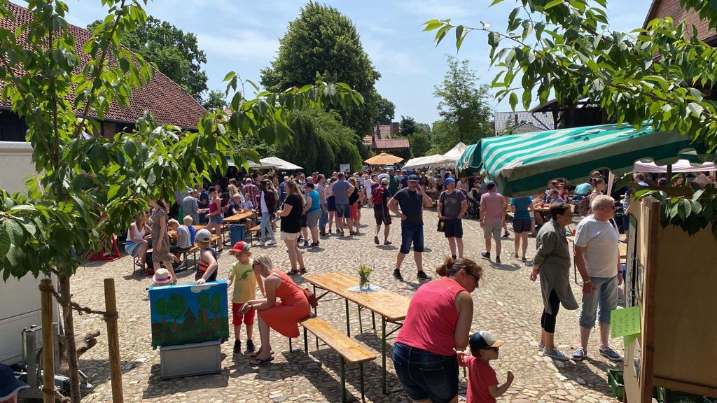 Das Bild zeigt Menschen, die einen Hof besuchen